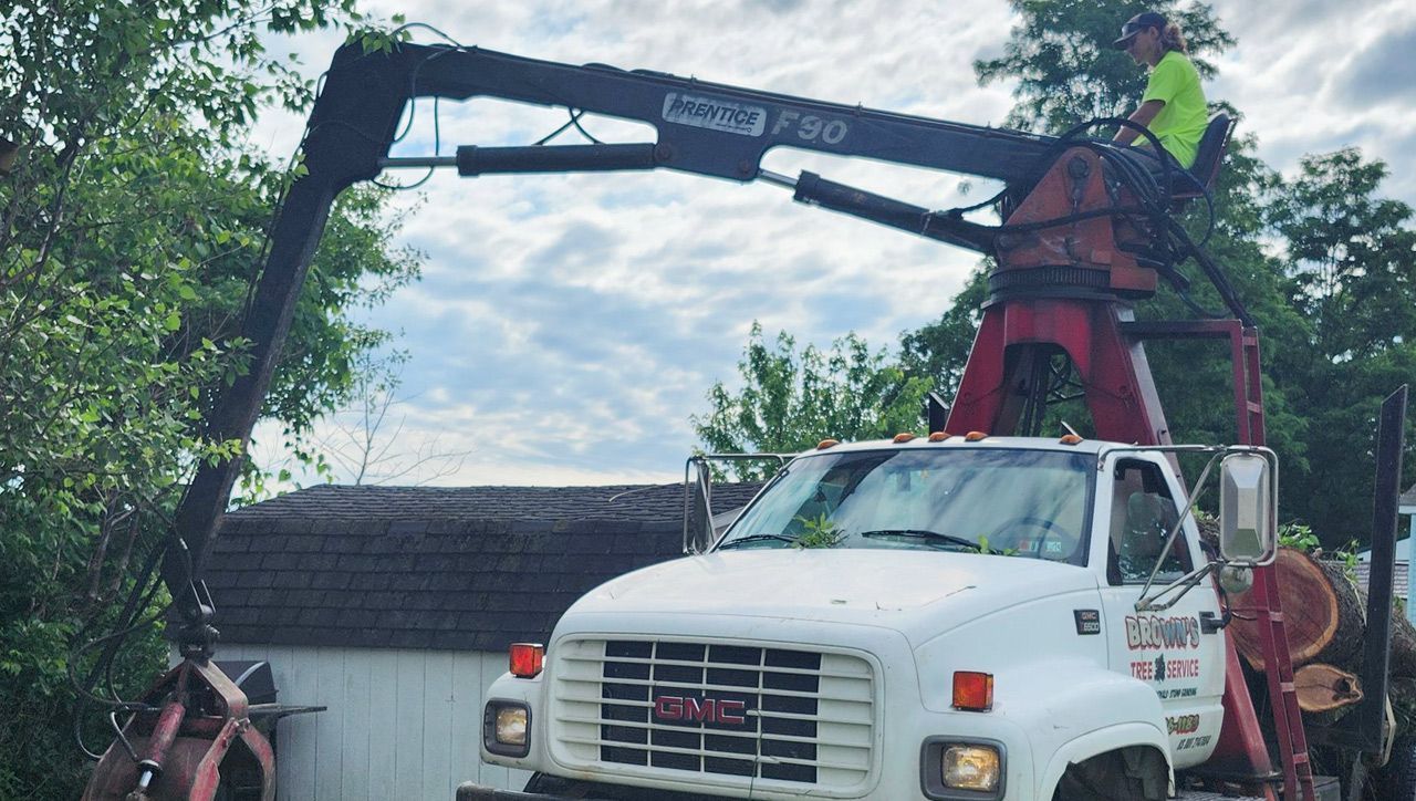 A man is standing on top of a truck with a crane attached to it.