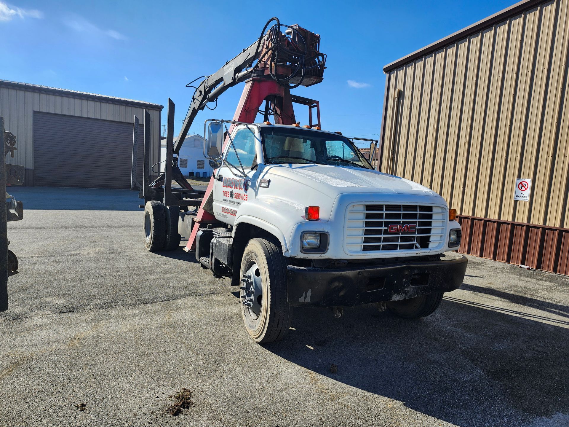 A white truck with a crane on top of it is parked in front of a building.