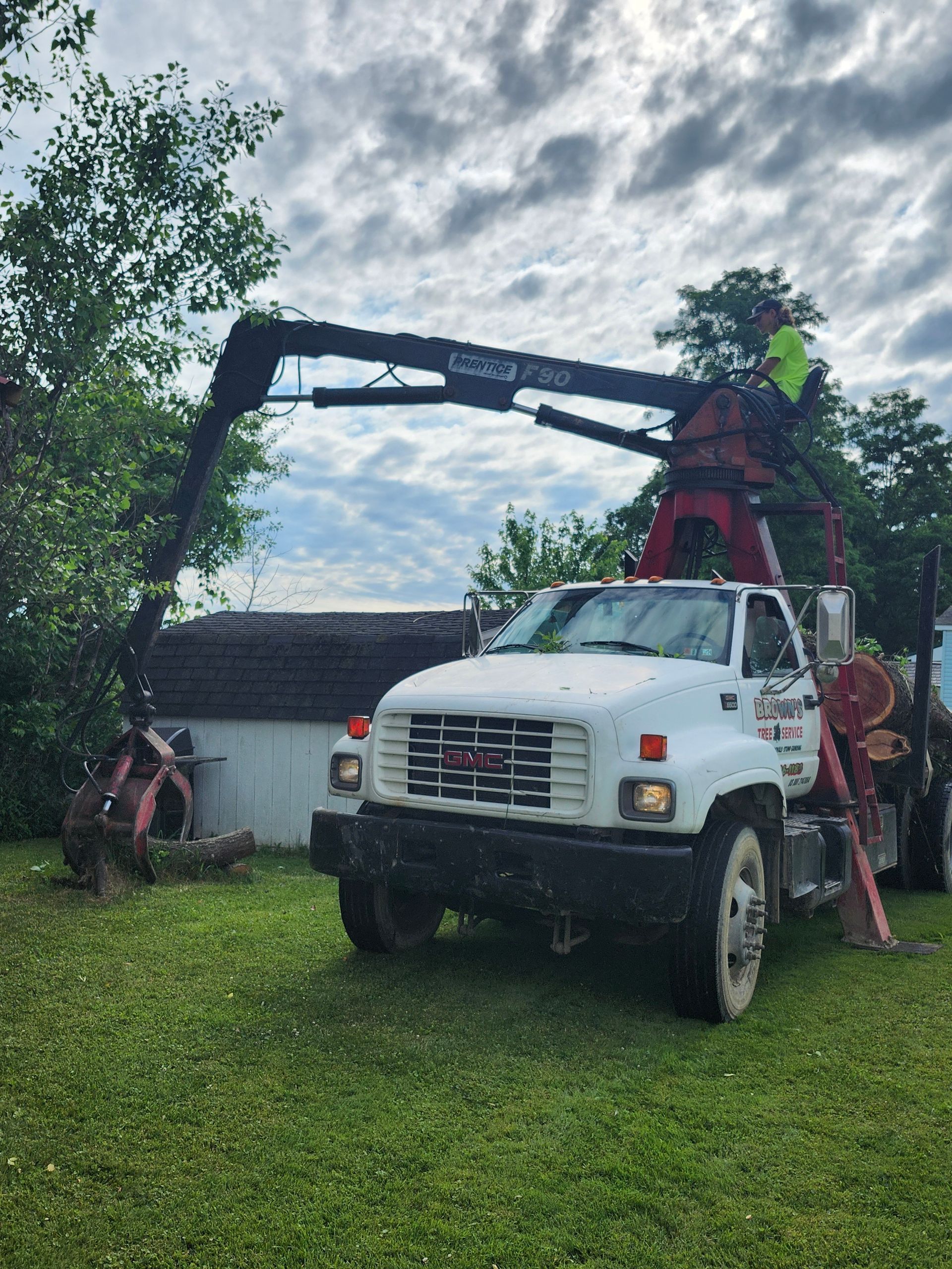 A white truck with a crane attached to it is parked in a grassy field.