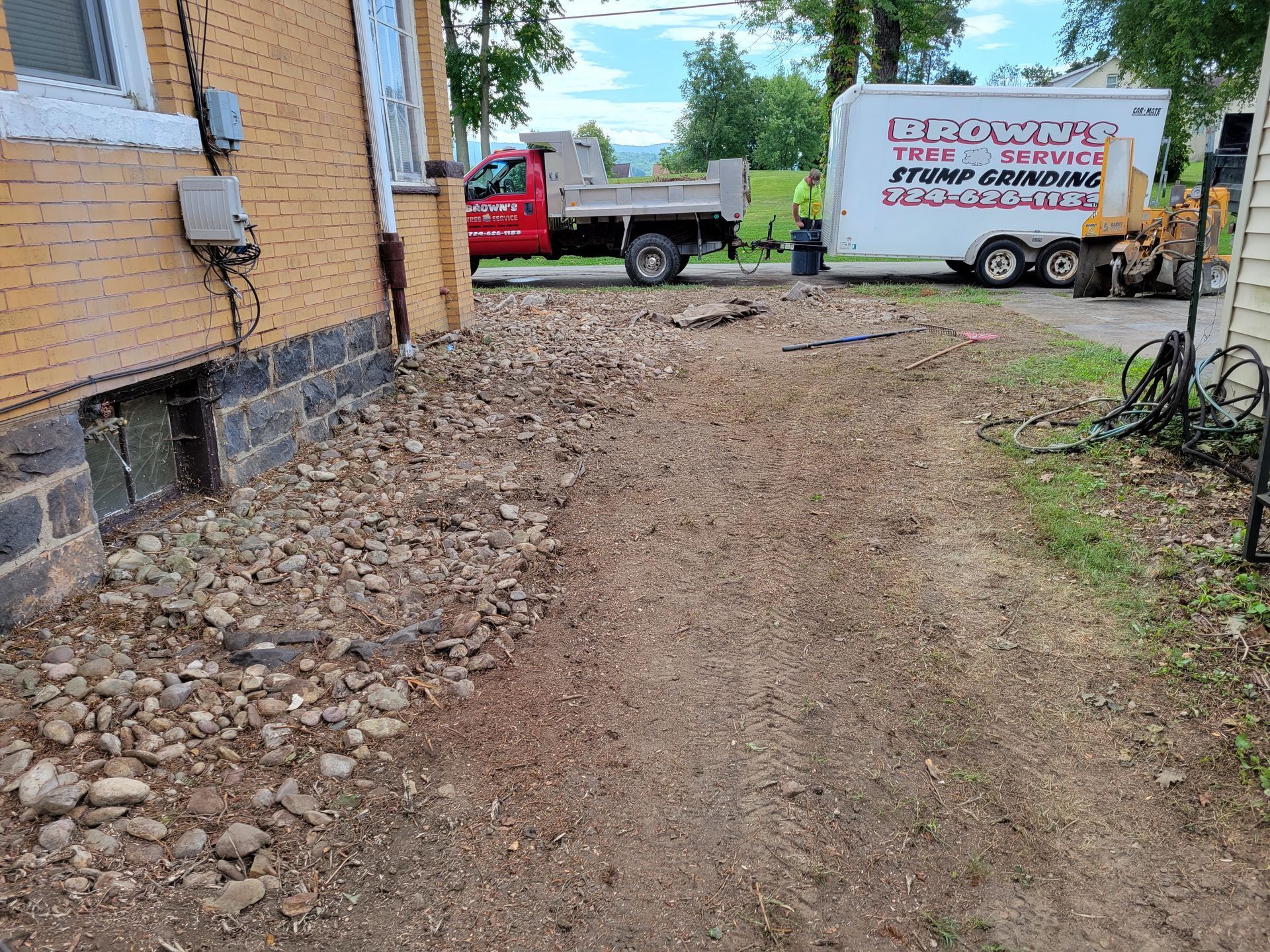 A man in a green jacket is working on a tree stump.