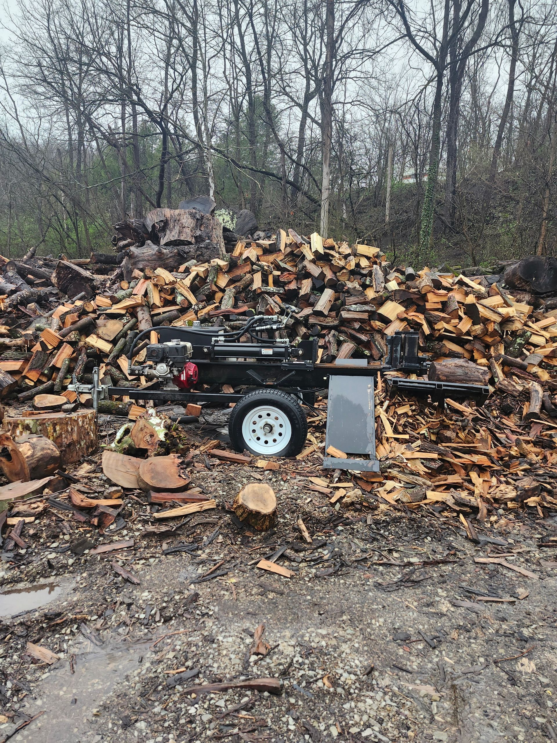 A log splitter is sitting on top of a pile of wood.