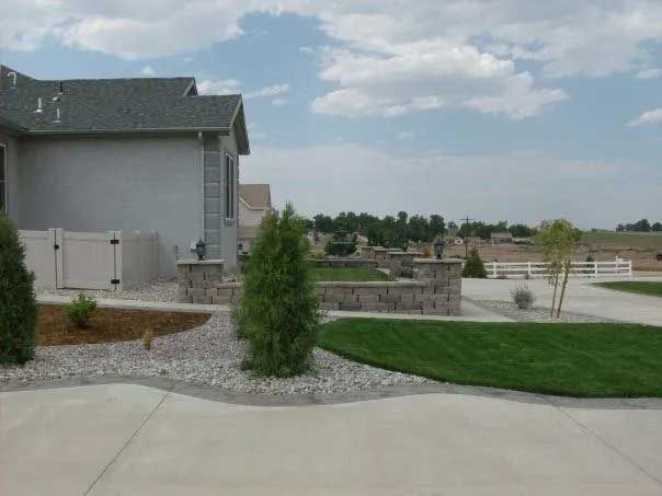 Suburban house with green lawn and landscape, cloudy sky.