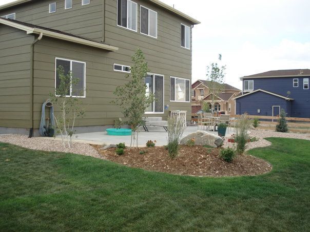Backyard with patio, landscaping, and a two-story house in a residential area.