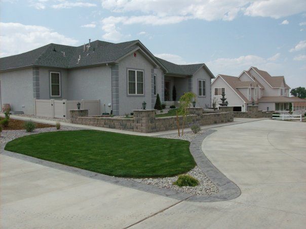 Grey houses with landscaped yards and driveway under a cloudy sky.