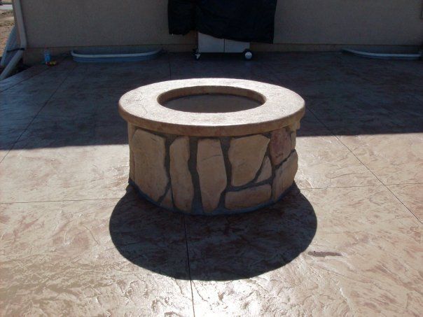 Stone fire pit on a stamped concrete patio, with a dark shadow.