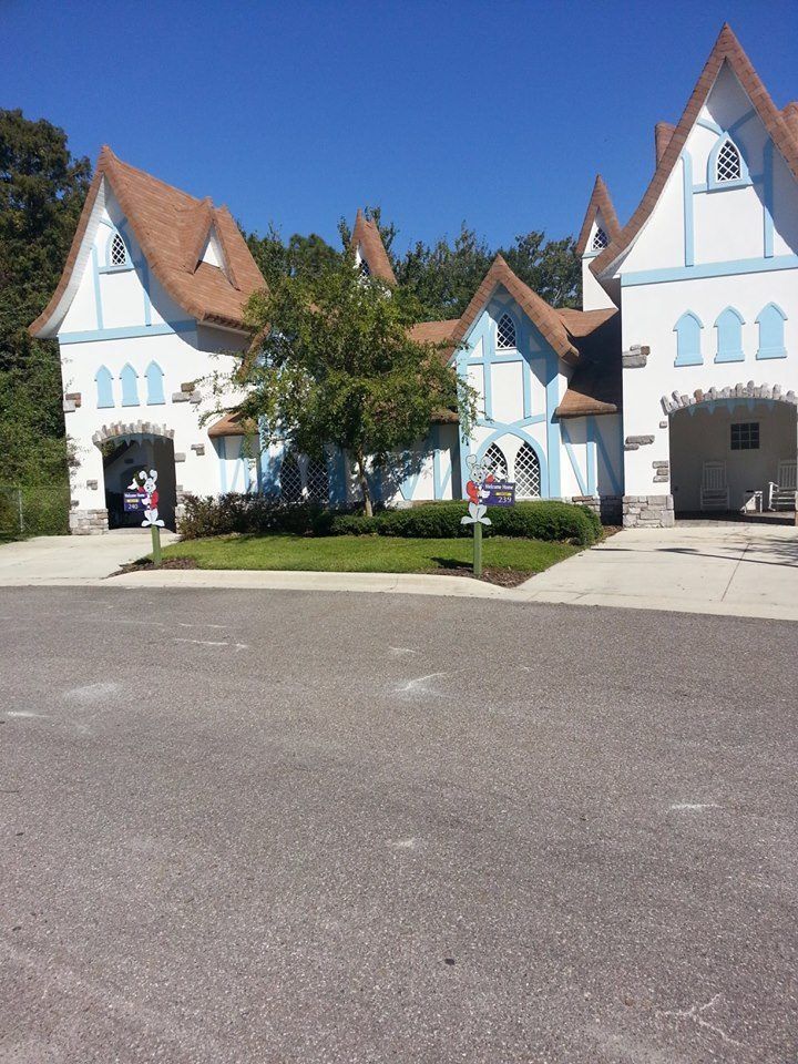 Fairytale-style white and blue buildings with brown roofs and archways; bright sunny day.