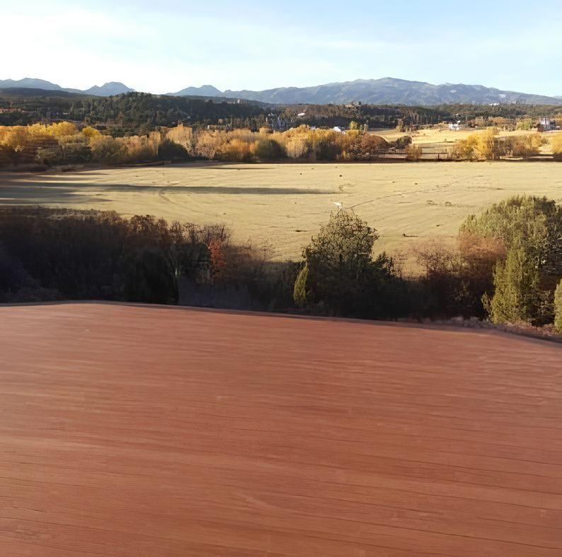 A wooden deck overlooking a field with mountains in the background