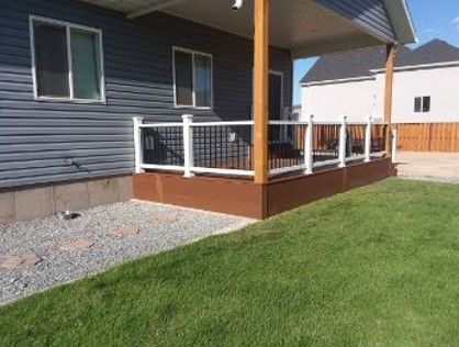 A deck with a white railing is in the backyard of a house