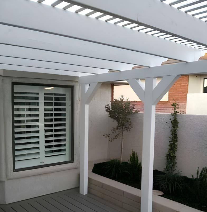A white pergola with shutters and a window