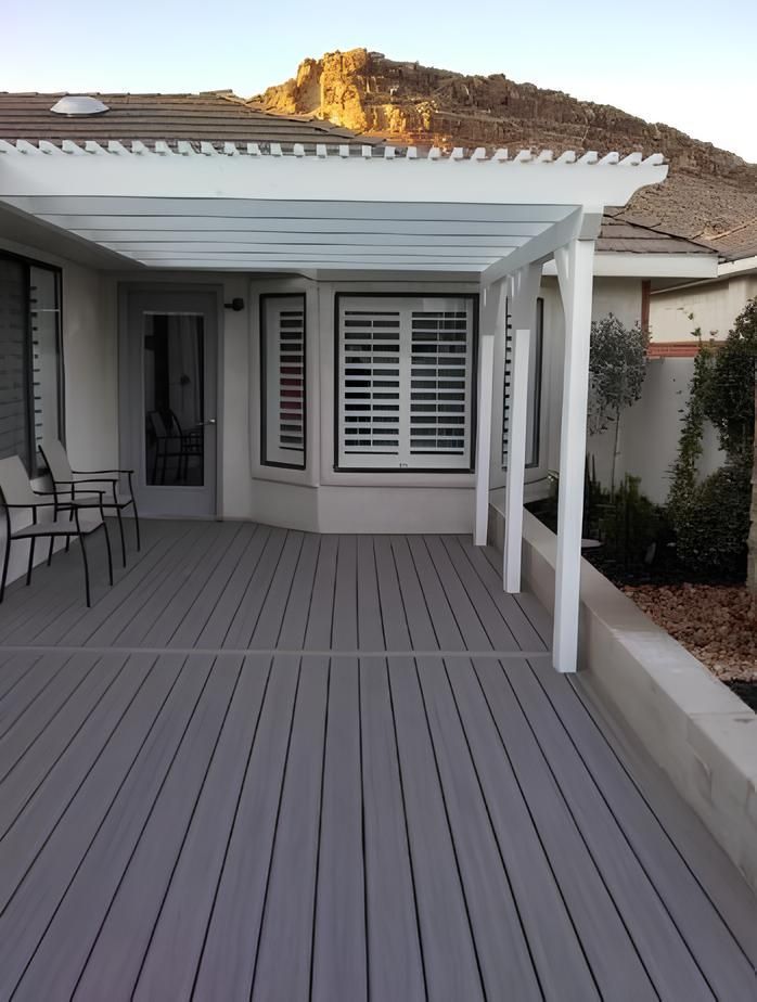 A deck with a white pergola over it