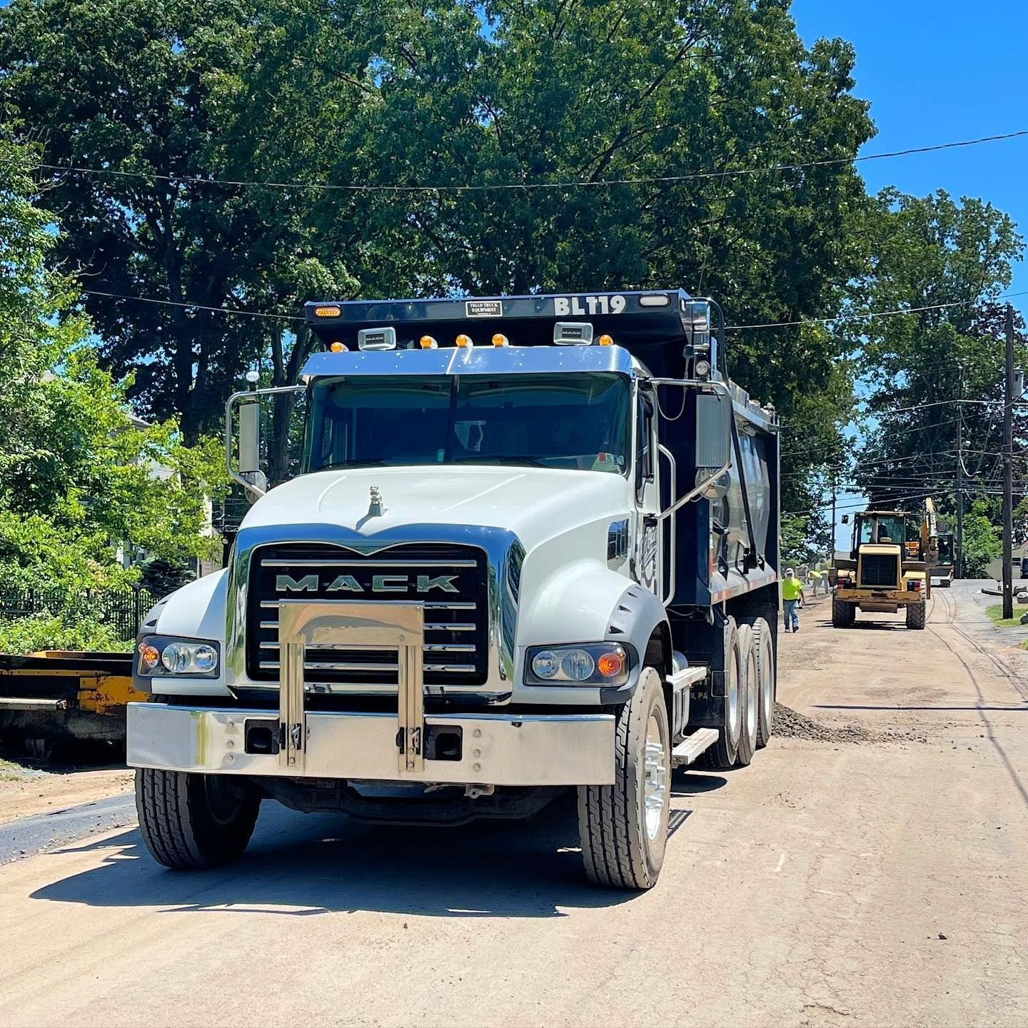 A mack dump truck is driving down a street