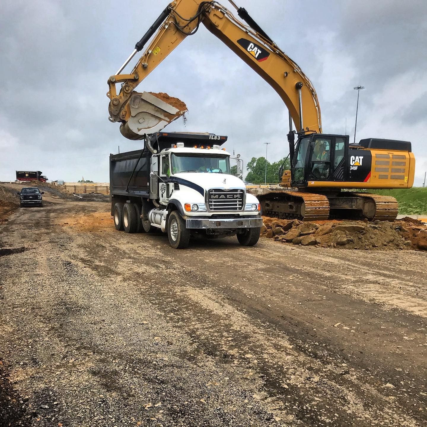 A dump truck is being loaded with dirt by a cat excavator