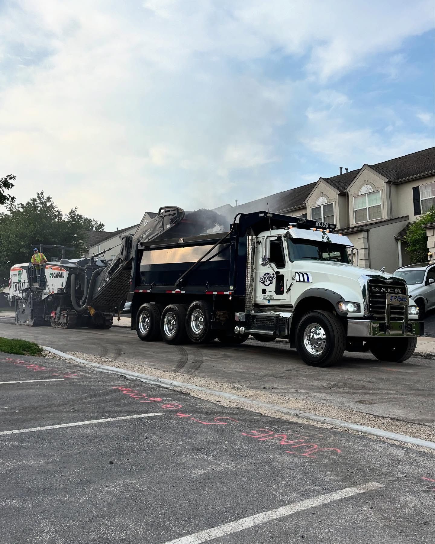 A dump truck is parked in a parking lot next to a building.