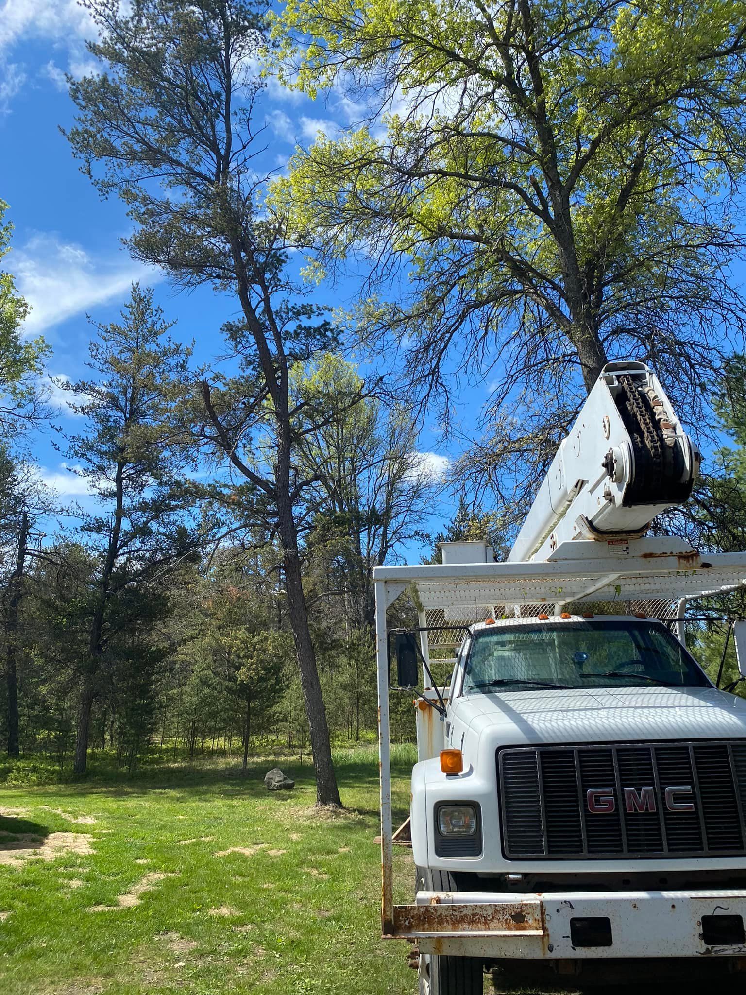 A white truck with a crane on top of it is parked in a grassy field.