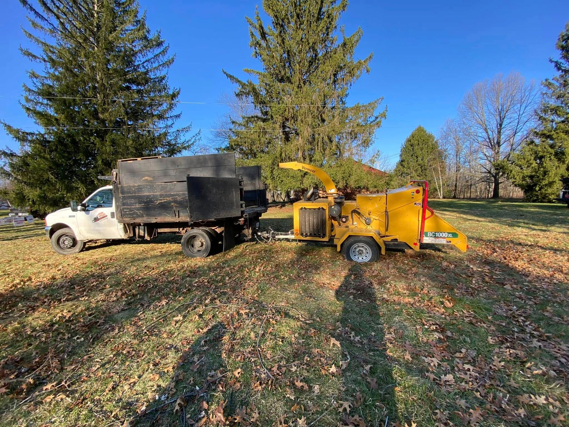 A truck is towing a tree chipper in a field.
