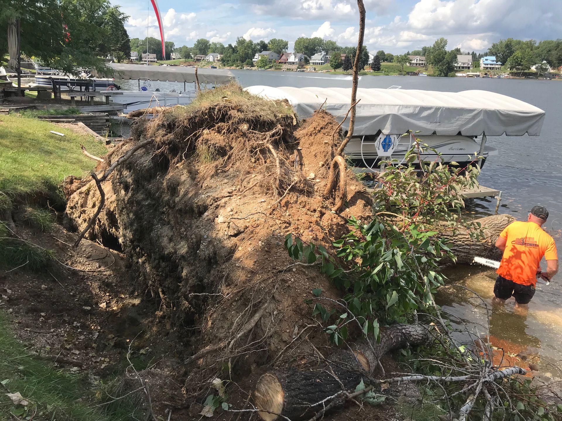 A man is standing next to a large pile of dirt next to a body of water.