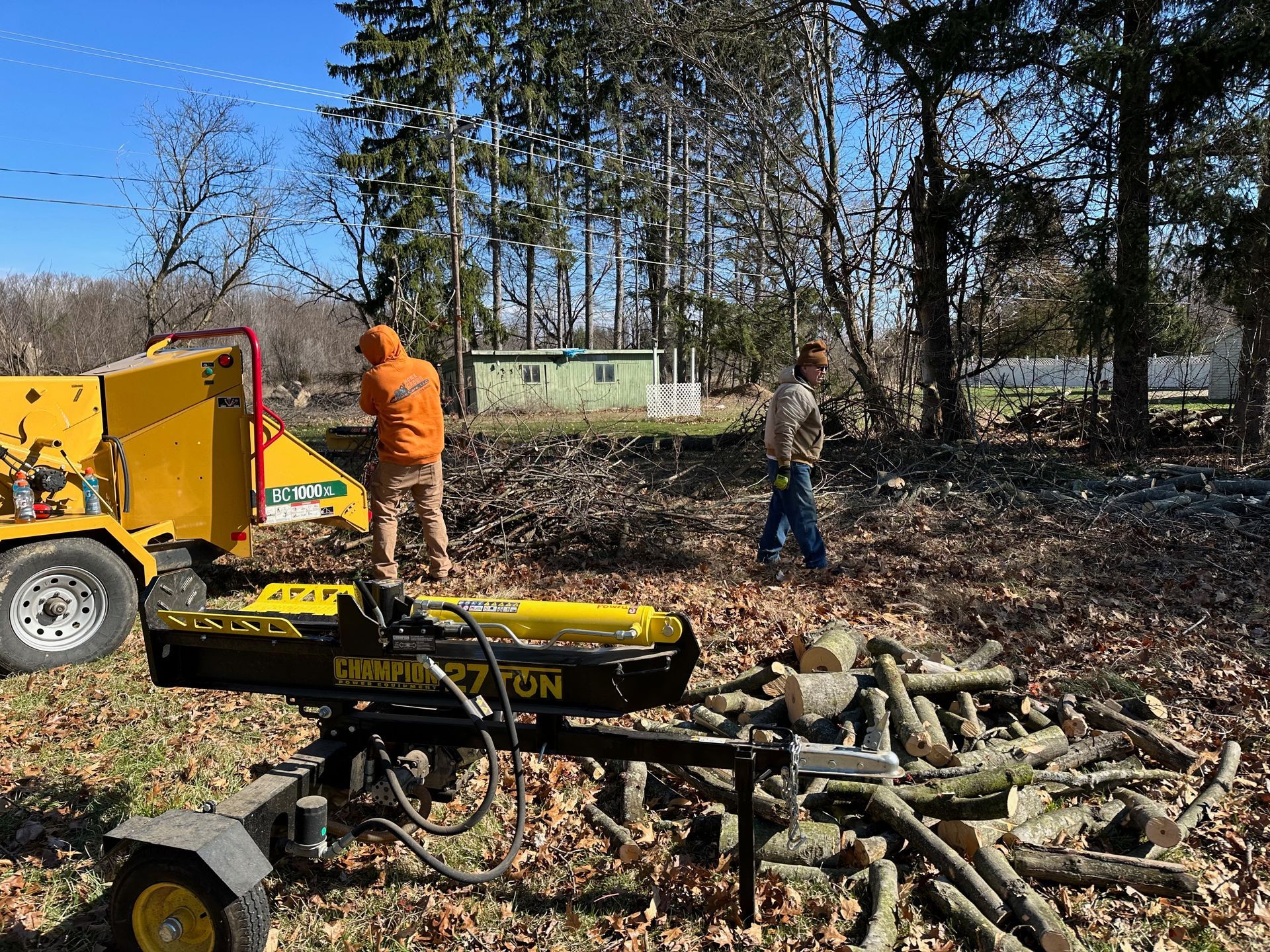 A man is standing next to a tree stump grinder in a field.