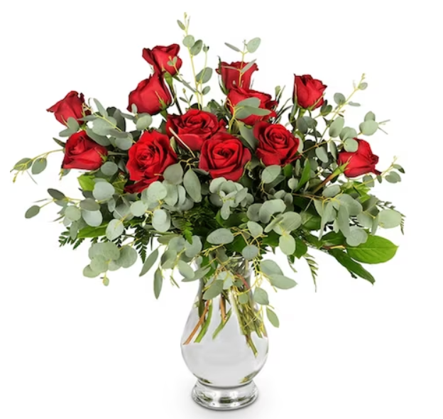 Red roses and green foliage in a silver vase.