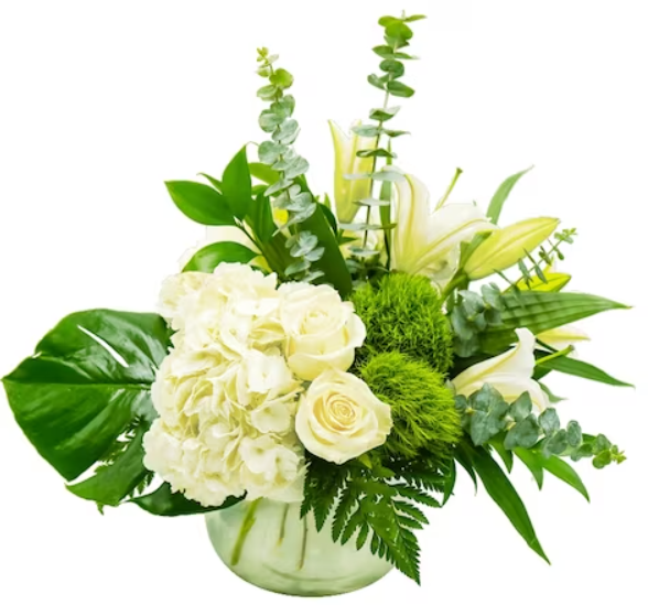 White and green floral arrangement in a glass bowl, featuring roses, lilies, hydrangea, eucalyptus, and a large monstera leaf.