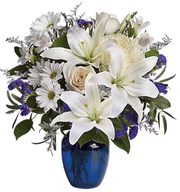 White lilies, daisies, and lavender flowers in a blue vase.