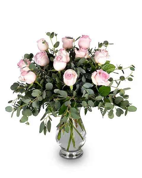 A vase filled with pink roses and greenery on a white background.