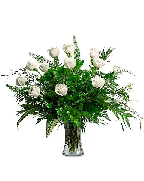A vase filled with white roses and greenery on a white background.