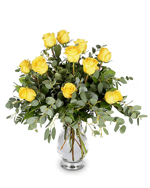 A vase filled with yellow roses and greenery on a white background.