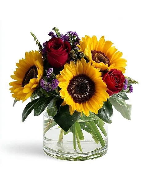 Sunflowers, red roses, and purple flowers in a clear glass vase.