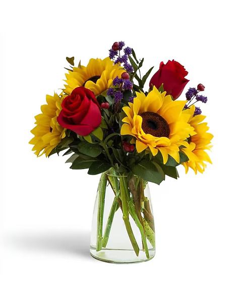 Bouquet of sunflowers, red roses, and purple flowers in a clear glass vase against a white background.