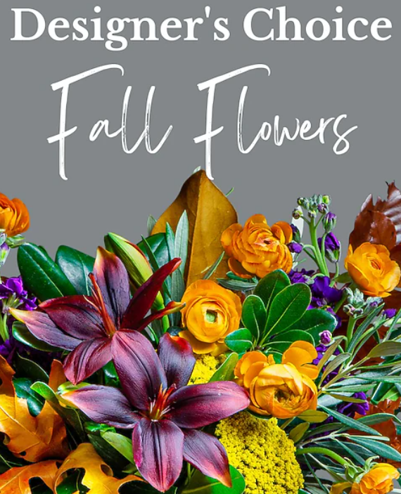 Designer's Choice Fall Flowers. Colorful bouquet with orange, purple, and yellow blooms and fall foliage against a grey background.