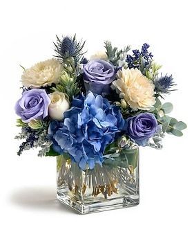 Blue and cream floral arrangement in a square glass vase. Includes roses, hydrangea, and thistle.