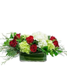 Floral arrangement in a glass vase: red roses, white and green hydrangeas, and greenery.