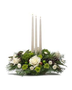 Christmas centerpiece with three white candles, white roses, green accents, and evergreen.