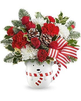 Floral arrangement in a polar bear mug, red and white flowers with pine cones and a striped bow.