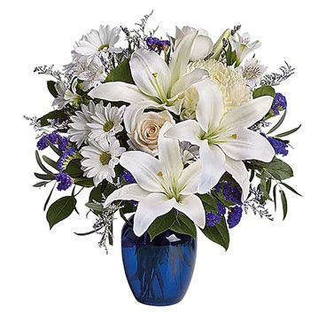 White lilies, daisies, and roses in a blue vase.