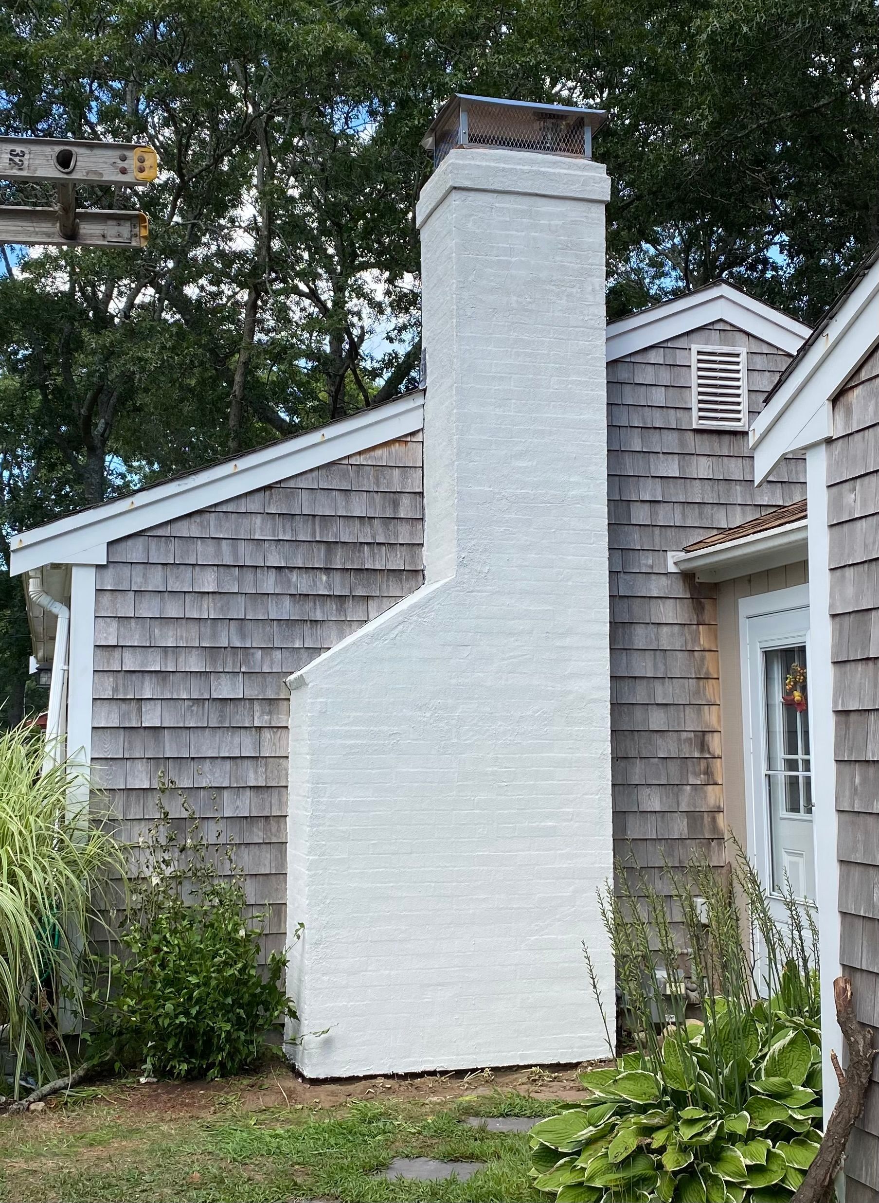 A white chimney is on the side of a house.