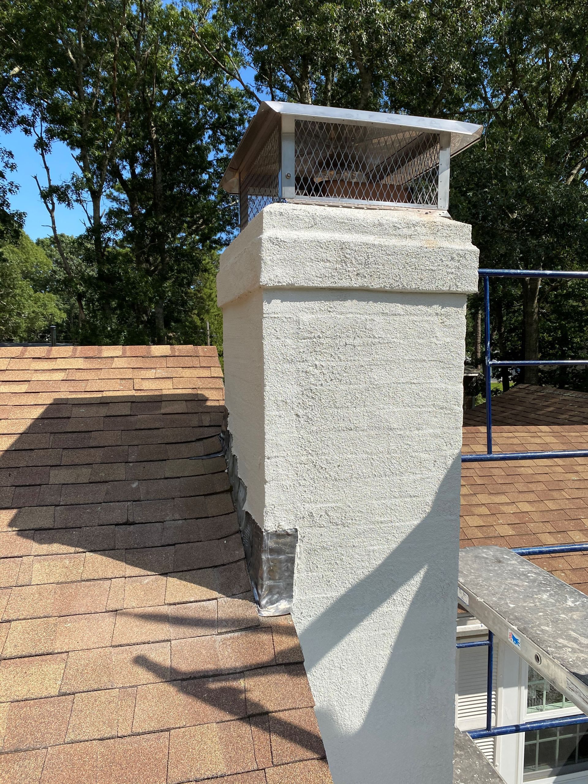A chimney on top of a roof with trees in the background