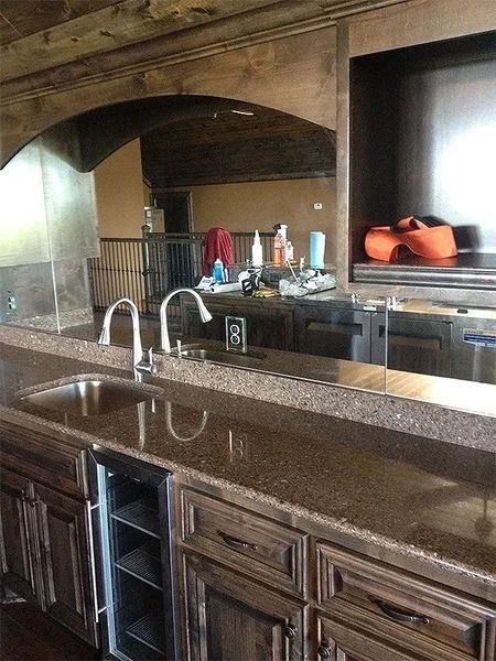 Stone kitchen with dark wood cabinets, granite countertop, double sink, and arched pass-through to another room