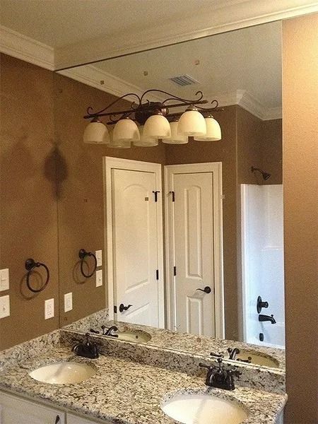 Bathroom vanity with granite countertop, double sinks, large mirror, and overhead light fixture.