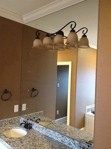 Bathroom vanity with granite countertop, wall mirror, and four-light fixture above sink.