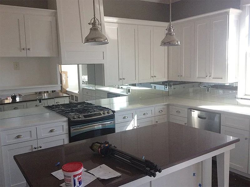 Bright white kitchen with island, cabinets, stove, sink, and two pendant lights