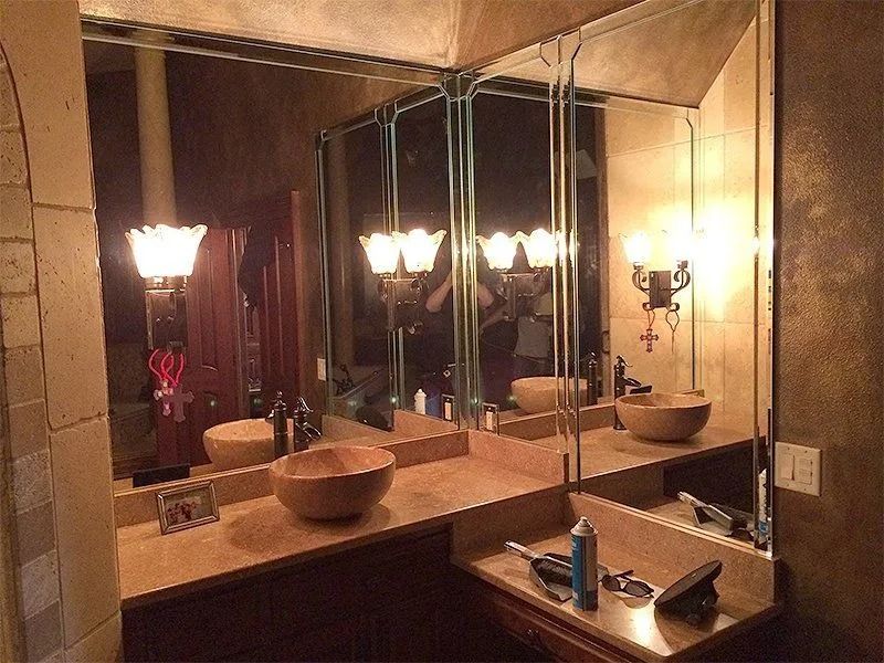 Bathroom vanity with large mirror, sink, and warm wall sconces reflecting the room.