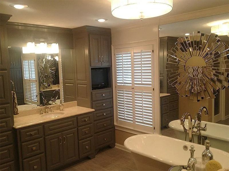 Elegant bathroom with dark wood vanity, double sinks, bathtub, and shuttered window blinds.