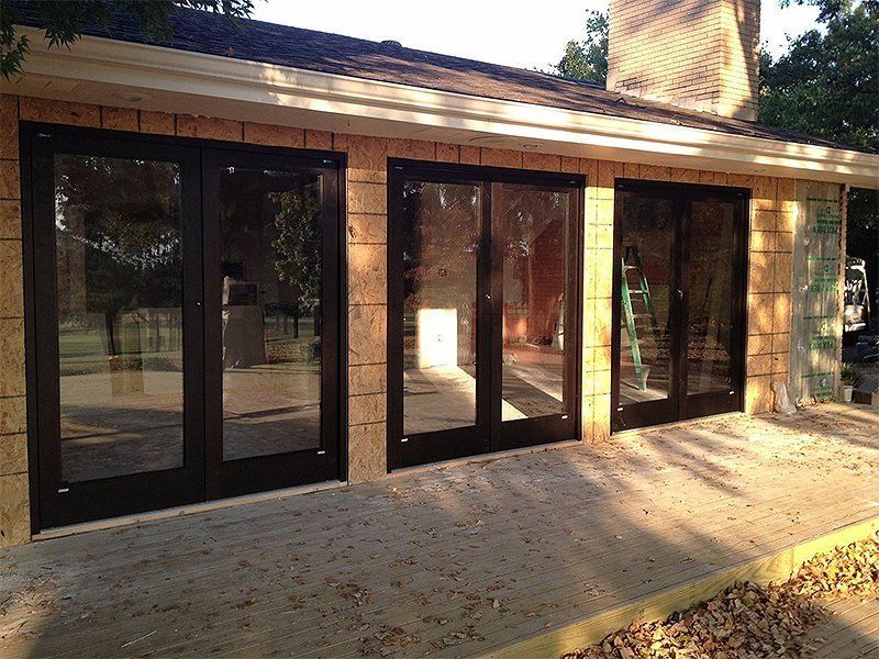 Brick patio with dark-framed glass doors on a house exterior in sunlight