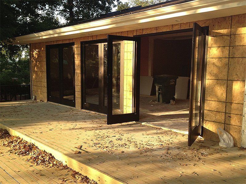 Open patio with folding glass doors on a tan brick house, lit by warm sunlight.