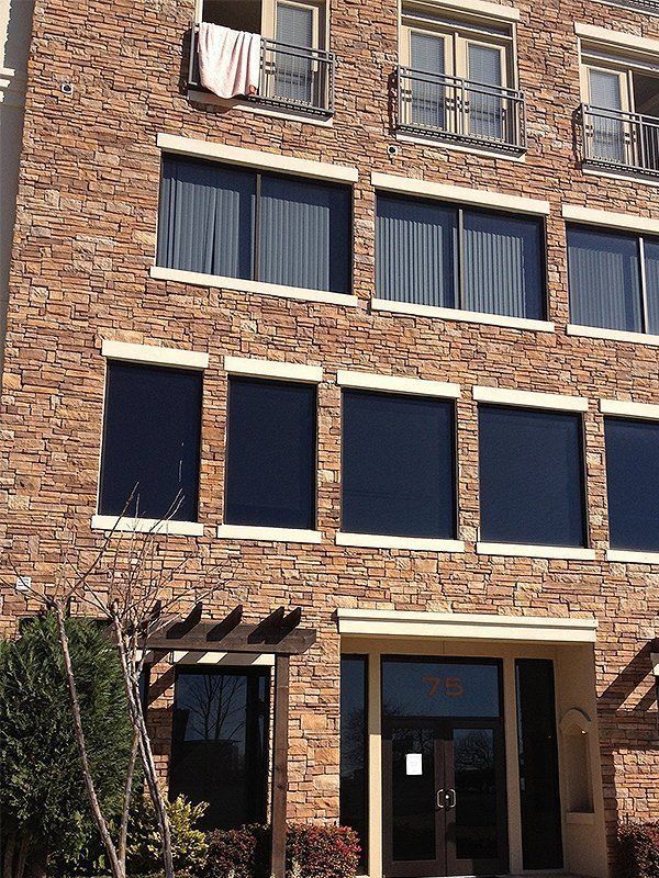 Brick apartment building facade with dark windows, balconies, and a ground-floor entrance