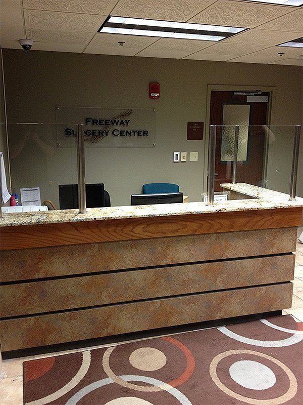 Empty hospital reception desk with marble counter and glass window at Procare Surgery Center