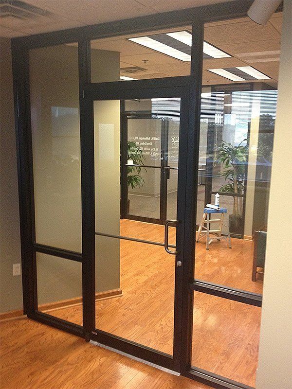 Glass-walled office entrance with a wood floor and a chair inside
