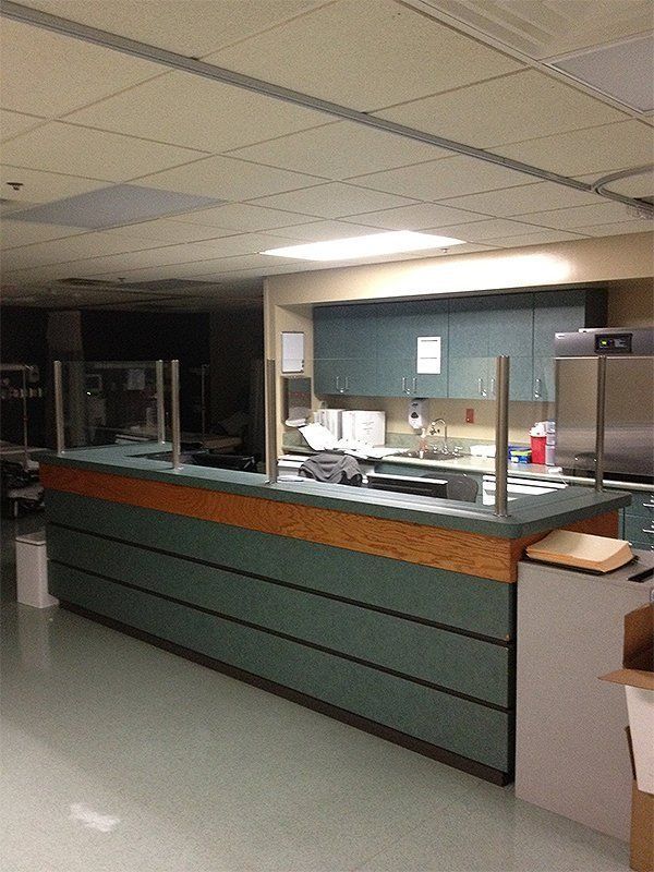 Empty hospital reception desk with green front panel and service window behind it