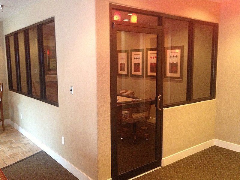 Office hallway with glass-walled corner room and framed art inside